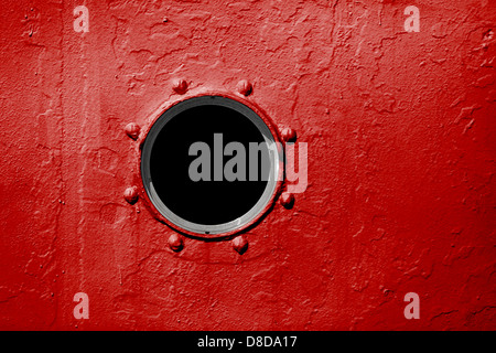 Bullauge an der roten Wand des alten Schiffes Stockfoto