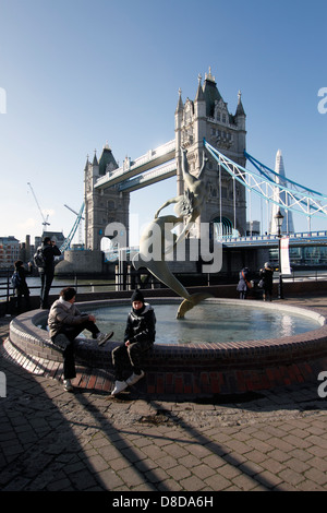 "Mädchen mit einem Delfin" entstand 1973 durch Künstler David Wynne. Tower Bridge im Hintergrund. Befindet sich am nördlichen Ufer der Themse in der Nähe von Tower Bridge. Die Statue sitzt direkt am Wasser vor dem Tower Hotel. Die Statue ist bekannt für seine Darstellung von Bewegung, so dass die Illusion der Figuren fliegen nicht unterstützt. Stein Stockfoto