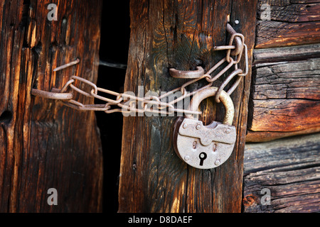 Alte rostige Vorhängeschloss und Kette auf den ländlichen Holztor Stockfoto