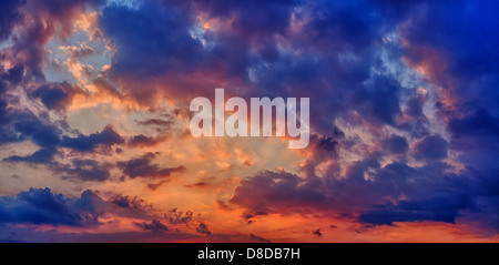 Sonnenauf- oder Sonnenuntergang mit Wolken. Panorama in dunklen Farben blau und orange Stockfoto
