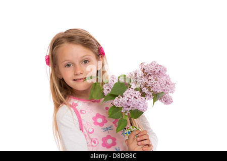 Glückliche kleine Mädchen mit langen Haaren trägt Sommerkleid und lila Blumen hält. Isoliert auf weißem Hintergrund. Stockfoto