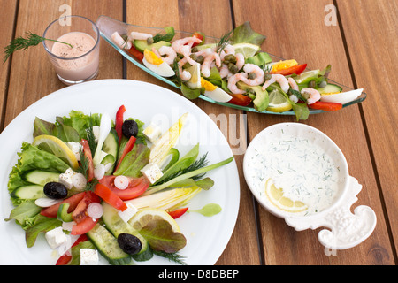 Zusammensetzung der griechischen Salat und Garnelen Cocktail auf einem Holztisch. Stockfoto