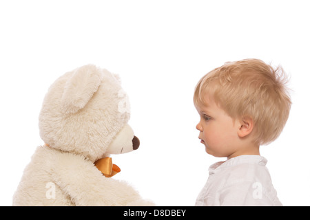 Nettes Kind mit blonden Haaren sucht ihren Teddy. Isoliert auf weißem Hintergrund. Stockfoto