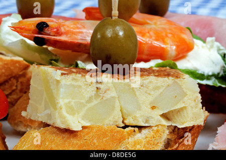 Spanische Tapas-Auswahl, mit spanische Tortilla garniert mit grünen Oliven und serviert auf knusprigem Brot im Vordergrund, Spanien. Stockfoto