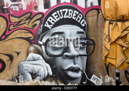 Streetart-Graffiti auf Mauer in Kreuzberg Hip Hop Stil männlichen Charakter spricht am Telefon mit "Kreuzberg" Kappe Berlin Deutschland Stockfoto