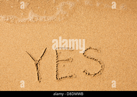 Ja - geschrieben im Sand am Strand Textur, weiche Welle des Meeres Stockfoto