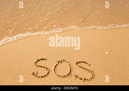 SOS - geschrieben im Sand am Strand Textur, weiche Welle des Meeres. Stockfoto