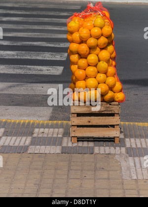 Ein großer Stapel von Orangen in einer Nylontasche Netting platziert auf einer Holzkiste von der Kandare zu verkaufen im Zentrum von Asunción, Paraguay. Stockfoto