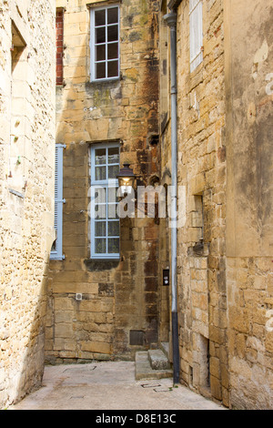 Schmale gepflasterte Straße unter mittelalterlichen Sandsteinbauten in charmanten Sarlat, Dordogne Region Frankreichs Stockfoto