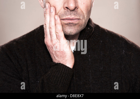 Ernster Mann berühren seine Wange, close-up Stockfoto