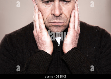 Ernster Mann berühren seine Wange, close-up Stockfoto