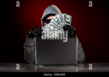 Junge Hacker in einer Sonnenbrille mit Laptop und Geld in die hand Stockfoto