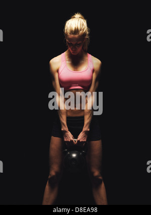 Fitness-Frau, die ein Krafttraining macht, indem sie eine schwere Kettlebell hebt Stockfoto