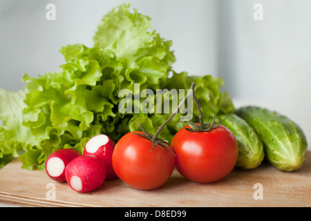 leckere Tomaten, Gurken, Radieschen und Salat auf dem Küchentisch Stockfoto