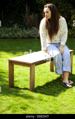 Frau sitzt auf der Gartenbank Stockfoto