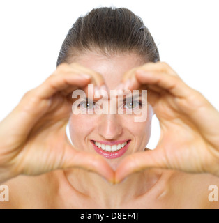 Lächelnde junge Frau durch Hände in Herzform Stockfoto