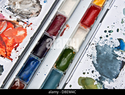 Dies ist ein Tablett mit Aquarellfarben in Pfannen und gemischt auf einer Palette eines Künstlers Materialien und Werkzeuge. Stockfoto