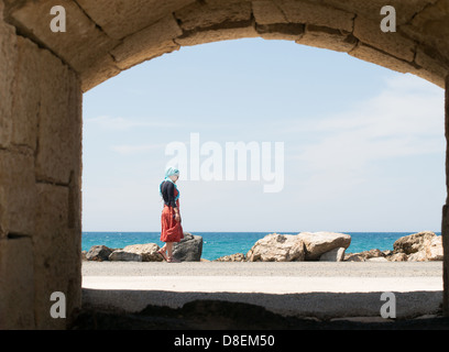 Frau, umrahmt von Bogen, zu Fuß entlang der Pier in Heraklion, Kreta, Griechenland Stockfoto