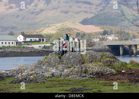 Touristen, die versuchen, einen Aussichtspunkt Blick auf Eilean Doonan Castle in Schottland, mit Blick auf Berge, See und Brücke zu bekommen. Stockfoto