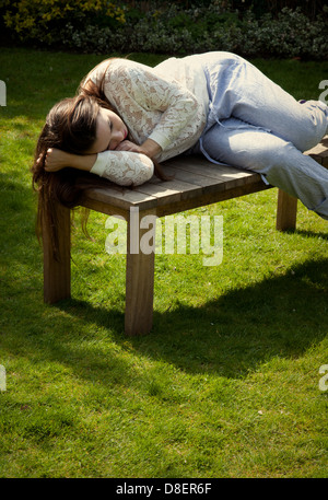 Frau liegt auf Gartenbank Stockfoto