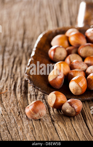 Ganze Haselnüsse in eine sehr alte hölzerne Schaufel auf rustikalen hölzernen Hintergrund Stockfoto