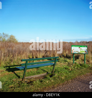 Eine grüne Bank in einem Naturschutzgebiet neben einer Informationstafel Stockfoto