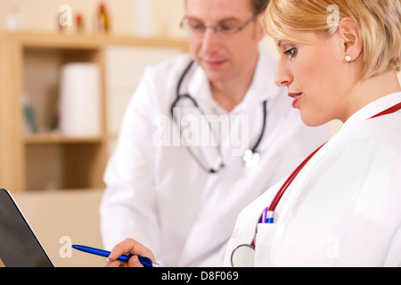 Zwei Ärzte - männlich und weiblich - Diskussion über Testberichte, die auf ihre Zwischenablage anzeigen Stockfoto