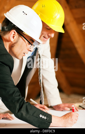 Architekt und Ingenieur und Landvermesser Diskussion Baupläne und Baupläne. Beide tragen Helme Stockfoto