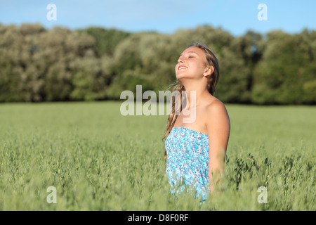 Schöne blonde Frau genießen den Wind auf einer grünen Wiese auf einer grünen Wiese Stockfoto