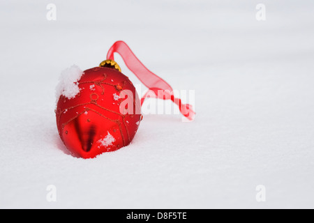 Eine einzelne rote Weihnachtskugel im Schnee liegen. Stockfoto