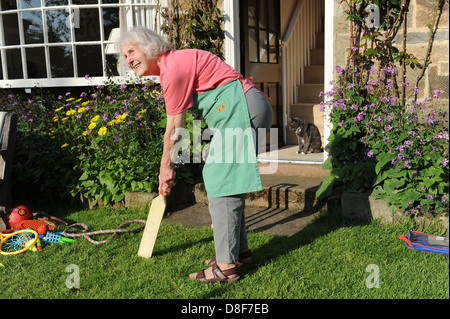 Ältere Großmutter ein Spiel Cricket im Garten für ihre Familie zu Hause in North Yorkshire. Stockfoto