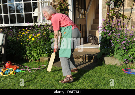 Ältere Großmutter ein Spiel Cricket im Garten für ihre Familie zu Hause in North Yorkshire. Stockfoto