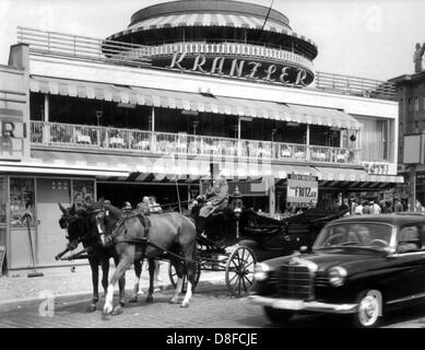 Stadt-Hektik und Biedermeier Romantik im Jahr 1960. Eine Kutsche mit Pferden und einer Mercedes-Limousine am Kurfürstendamm in Berlin vor dem berühmten Café Kranzler. Stockfoto