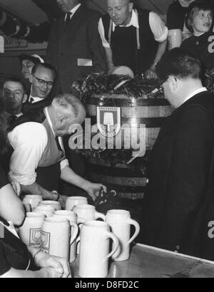 Ehemaliger Bürgermeister Thomas Wimmer tippt den ersten Lauf auf dem Oktoberfest (September 1960). Sein Nachfolger im Amt, Bürgermeister Dr. Hans-Jochen Vogel, schaut ihm zu lernen, wie man den Lauf im Folgejahr zu tippen. Stockfoto