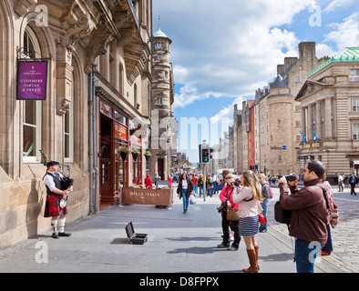 Touristen, die gerade einer Piper spielt auf der High Street in Edinburgh Altstadt die royal Mile Midlothian Schottland UK GB EU Europe Stockfoto