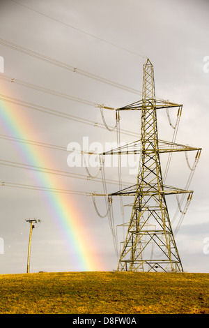 Ein Regenbogen über Strommasten Kernkraftwerk Wylfa auf Anglesey, Wales, UK verlassen. Stockfoto