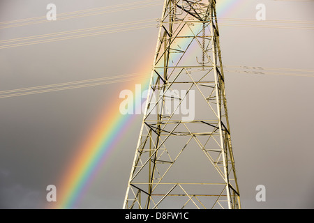 Ein Regenbogen über Strommasten Kernkraftwerk Wylfa auf Anglesey, Wales, UK verlassen. Stockfoto