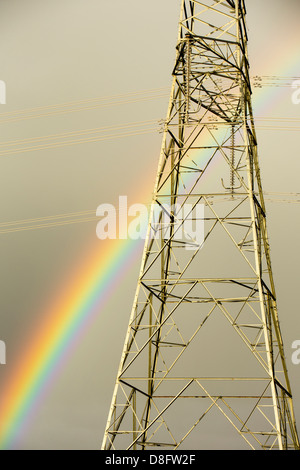 Ein Regenbogen über Strommasten Kernkraftwerk Wylfa auf Anglesey, Wales, UK verlassen. Stockfoto