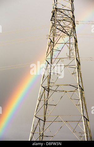 Ein Regenbogen über Strommasten Kernkraftwerk Wylfa auf Anglesey, Wales, UK verlassen. Stockfoto