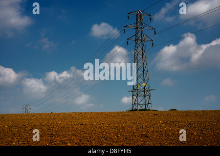 Stromleitungen erstrecken sich über East Sussex Ackerland. Stockfoto