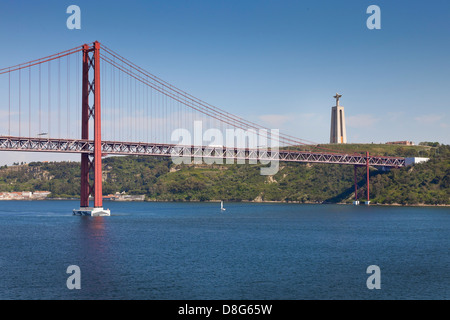 25 de Abril Brücke, Lissabon, Portugal, mit der großen Christus-Statue (Cristo Rei) im Hintergrund. Stockfoto