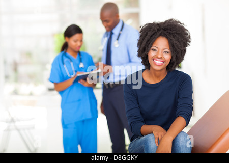 hübsche junge afrikanische Frau sitzen auf Bett zu prüfen und warten auf ärztliche Untersuchung Stockfoto