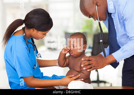 Afro American männlichen Kinderarzt und Krankenschwester untersuchen einen Babyjungen in Klinik Stockfoto