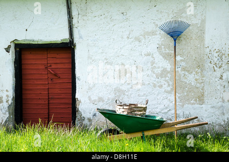 Alte Gartengeräte an und alte verwitterte Wand. Stockfoto
