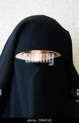 Arabische Frau, die mit traditionellen schwarzen Niqab Gesicht abdecken Stockfoto