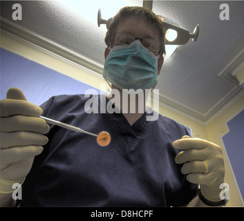 Ein Zahnarzt bei einem Patienten mit seinem Spiegel einsatzbereit Stockfoto