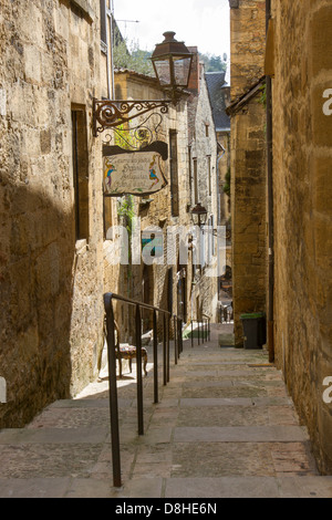 Stufen, die nach unten schmale gepflasterte Straße zwischen Sandsteingebäude im charmanten Sarlat, Dordogne Region Frankreichs Stockfoto