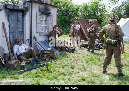 Britische Soldaten Entspannung unter den zerstörten Gebäuden während der Overlord, d-Day-Re-Enactment Denmead 2013 Stockfoto