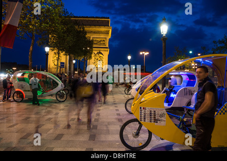 Paris, Frankreich. Velo-taxis (Velotaxis) und Cyclobulles warten in der Nähe des Arc de Triomphe als Menschen vorbei. Stockfoto