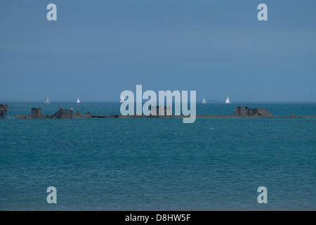 Arromanches, Normandie, Frankreich. Reste der "Mulberry" künstliche Hafen mit Booten im Hintergrund aus dem zweiten Weltkrieg. Stockfoto